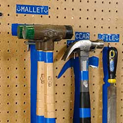 Tools are hung on a pegboard in locations marked by lean/5S labels.