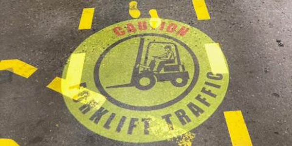 A red stop sign and a yellow line projected from above onto a walkway within a manufacturing environment.