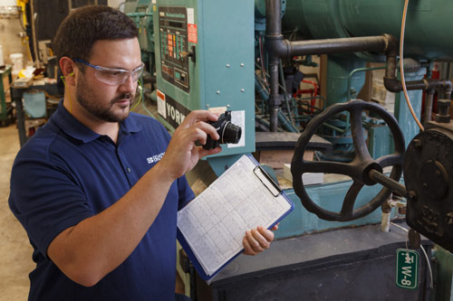 A safety professional taking a photo of manufacturing equipment.