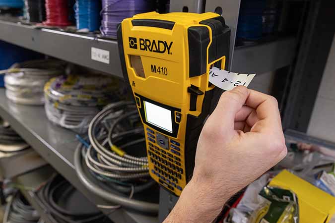 A worker prints a label using an M410 printer that is conveniently stuck with a magnet to a shelf rack.