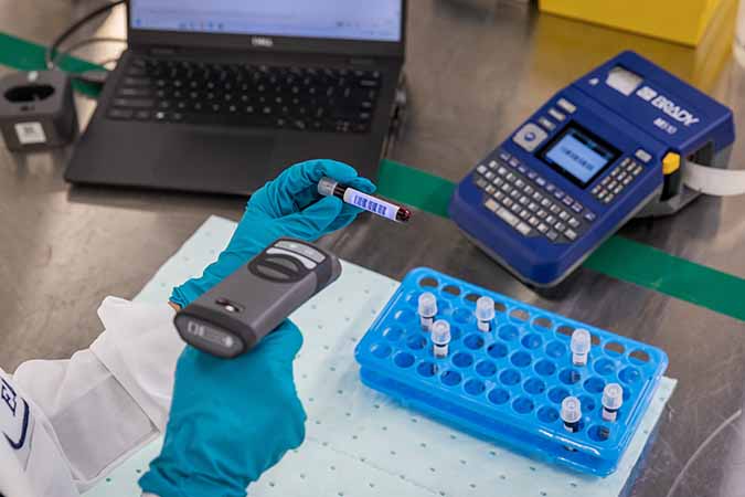 A lab technician printing and scanning barcodes for vials.