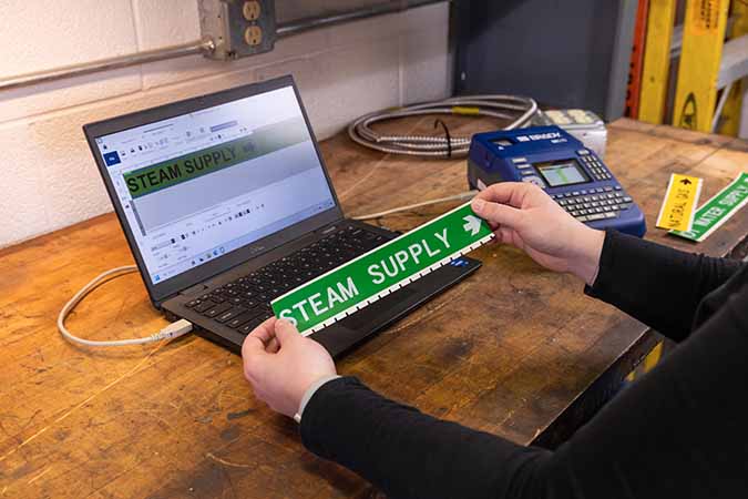 A person using Brady Workstation and an M510 label printer to make pipe markers.