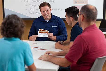 A manager teaching a group of new employees about the basics of arc flash safety.