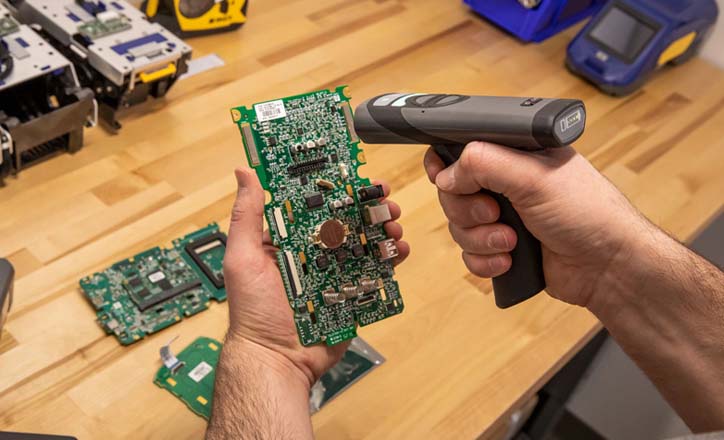 An individual uses a CR2700 barcode scanner to read a Brady barcode label on a circuit board.