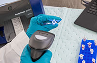 A Brady i5300 printer and barcode label scanner are being used in a laboratory to tag and identify vials.