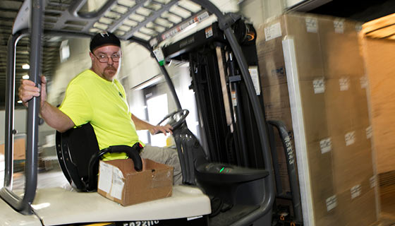 Man driving forklift moving boxes