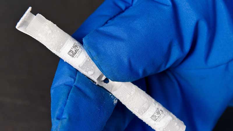 A close-up view of three plastic test tubes covered in ice, each marked with a durable Brady cryogenic barcode lab label.