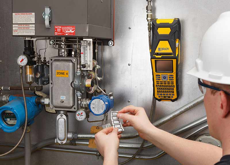 A worker applying heat-resistant labels to an industrial machine.