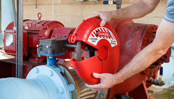 An individual applying a lockout device to a valve handle as part of their lockout tagout process.