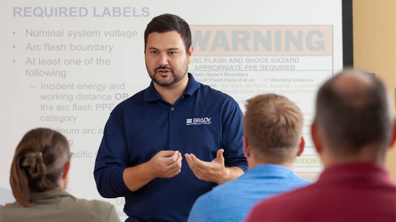 An expert from Brady delivers an arc flash training session to a conference room full of workers.